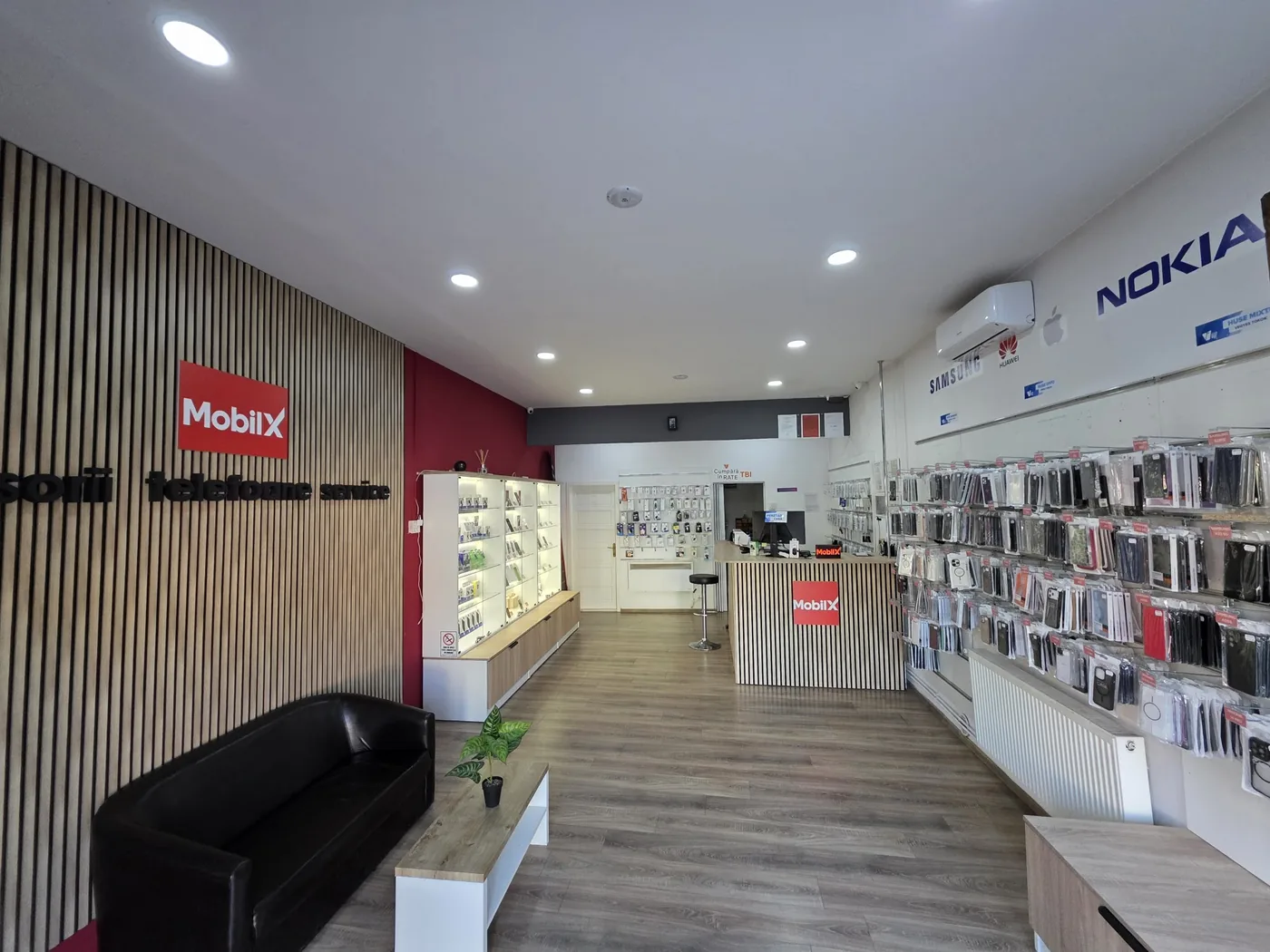 Interiorul magazinului MobilX: perete cu lambriu de lemn, canapea, vitrine cu accesorii